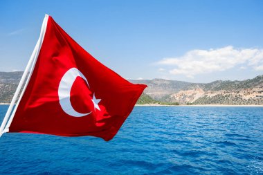 Güneşli bir günde Türkiye'nin Akdeniz'e karşı rüzgarda sallayarak bayrak.