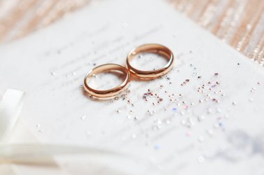 Altın alyans parlak rhinestones davetle kağıt üzerinde. Düğün detayları, sevgi ve evlilik sembolü.