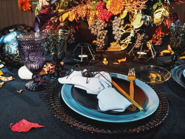 Tablo Cadılar Bayramı tarzı görev. Buket kırmızı çiçekler, dekoratif örümcekler, yazı ve Gotik ile kabak asma gözlük siyah masa örtüsü. Tatil dekorasyon.