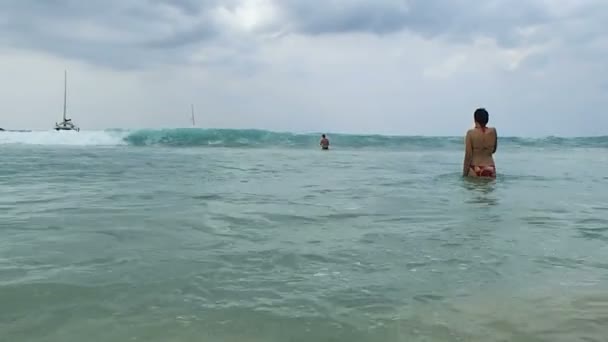 Chica en un traje de baño brillante bañándose en las olas. Seasurf en la playa de Nai Harn, isla de Phuket, Tailandia . — Vídeo de stock