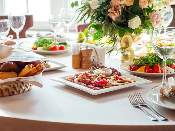 Tablo için düğün ziyafet çatal ve vazo çiçekleri ile görev yaptı. Salatalar, mezeler ve gözlük şarap ile.