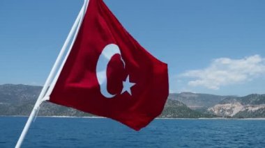 Güneşli bir günde Türkiye'nin Akdeniz'e karşı rüzgarda sallayarak bayrak.