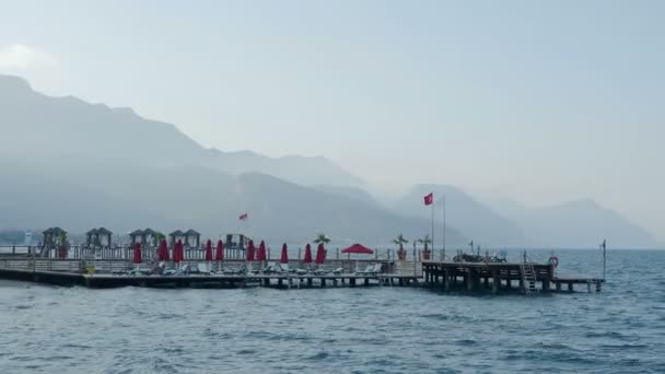 Pôr do sol na praia. Típico hotel turco com espreguiçadeiras e pontão de madeira. Kemer, Turquia . — Vídeo de Stock