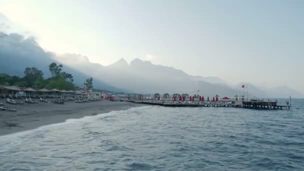 Sunset on the beach. Typical turkish hotel with sun loungers and wooden pontoon. Kemer, Turkey. — Stock Video