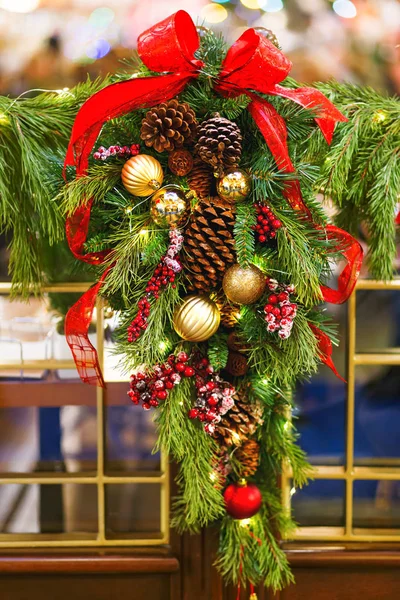 Fir tree wreath decorated with berries, pine cones and shiny balls for Christmas and New Year celebration.