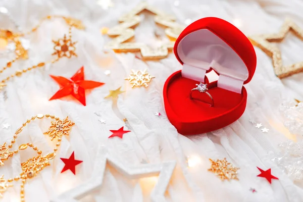Christmas and New Year holiday background with decorations and engagement ring with diamond in gift heart box.