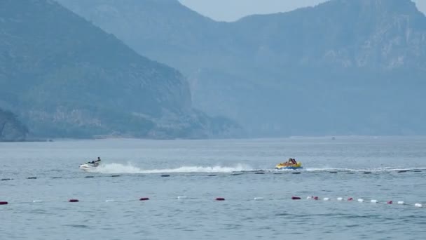KEMER, TURKEY - May 12, Tourists have fun in the water attraction - inflatable sofa that moves with jet ski. — Stock Video