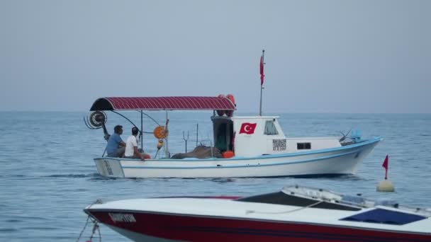 Κεμέρ, Τουρκία - Μαΐου 12, 2018. Οι άνδρες μιλούν στο μηχανοκίνητο σκάφος που κινείται. Όχημα που πλέει στη θάλασσα παρελθόν τις σημαδούρες. — Αρχείο Βίντεο