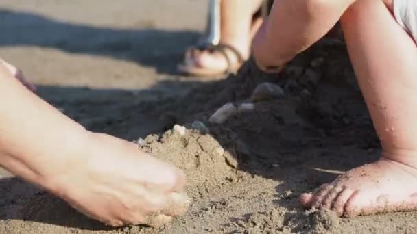 Barnet leker med föräldrar på stranden. Barnen händerna fulla med sand. Utomhus spel. — Stockvideo