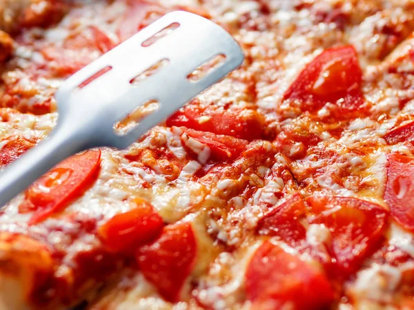 Pizza Margarita with baked ingredients - cheese with ham and tomatoes. Traditional italian cuisine.