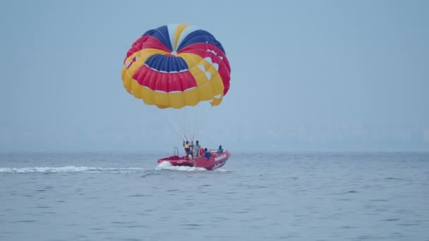 КЕМЕР, ТУРКИ - 12 мая, Туристы веселятся в водной аттракцион - парасейлинг. Человек с парашютом движется с моторной лодкой . — стоковое видео