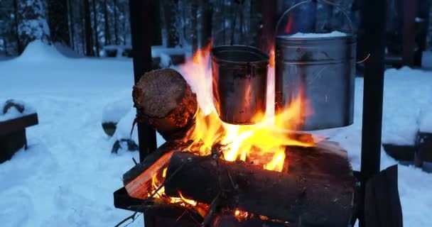 Cucinare zuppa su una pentola di fuoco. Sciogliere la neve come acqua per il tè. Campeggio invernale nella foresta . — Video Stock