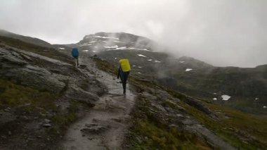 Kayaların arasında turistler devam et. Ünlü dönüm noktası - Trolltunga, Troll dil yolu. Norveç'te hiking.