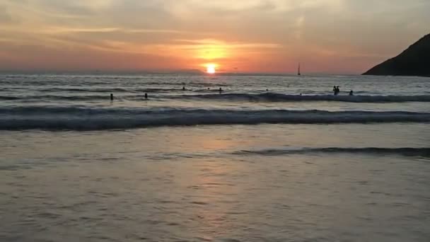 Phuket, Thailand - 25 oktober 2012. Mensen zwemmen in zee bij zonsondergang. Nai Harn beach. — Stockvideo