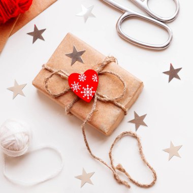 DIY hediye Kraft kağıt sarılı. Hediyeler ile kırmızı kalp simgesi olan beyaz ve kırmızı iplik bağlı. Noel ve Yılbaşı tatil arka plan.
