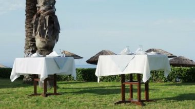 Tabloları, hizmet yeşil çim akşam yemeği için. Avuç içi altında açık hava Akdeniz yemek. Sahil akşam yemeği.