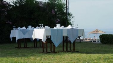 Tabloları, hizmet yeşil çim akşam yemeği için. Avuç içi altında açık hava Akdeniz yemek. Sahil akşam yemeği.