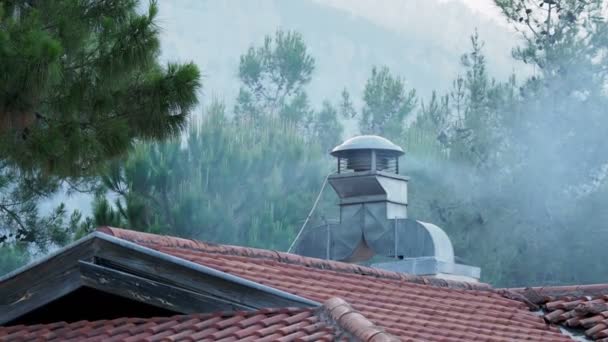 屋根の上の煙突から出てくる煙。換気のタービンは取り組んでいます。台所から蒸気や煙の抽出. — ストック動画