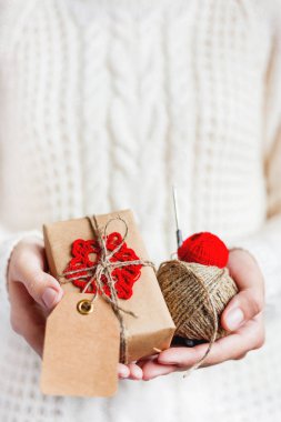 Beyaz örgü kazak Kraft kağıt kırmızı tığ işi kar tanesi ile paketlenmiş hediye tutan kadın. DIY Noel ve yeni yıl, St Sevgililer günü hediyesi.