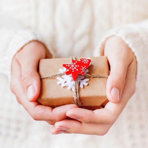 穿着针织毛衣的妇女拿着用工艺纸包装的圣诞礼物 上面塞满了毛毡雪花和红杉树 新年迪的礼物 — 图库照片