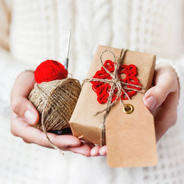 穿着白色针织毛衣的妇女 拿着一件用工艺纸包装着红色钩针雪花的礼物 亲爱的圣诞节或新年 情人节礼物 — 图库照片