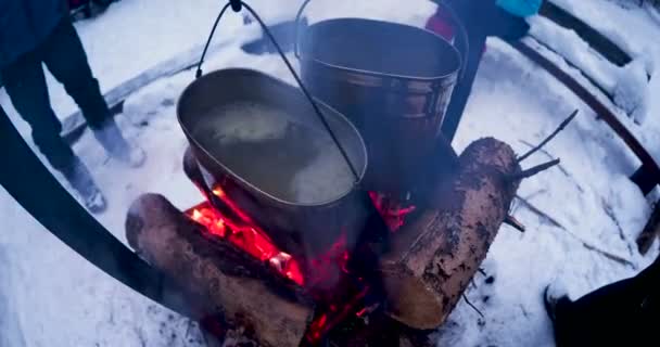 Cozinhar sopa em uma panela de fogo. Derreter a neve como água para o chá. Acampamento de inverno na floresta . — Vídeo de Stock