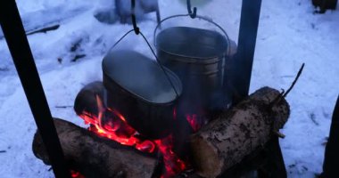 Bir yangın pot pişirme yemek. Çay için su olarak eriyen kar. Ormanda kamp kış.