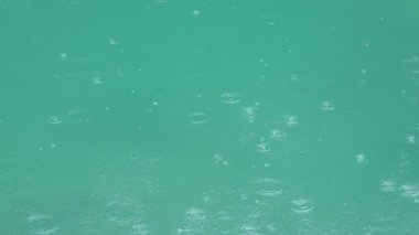 Yağmur damlası daireler ile su yüzeyi. Yağmur altında birikintisi.