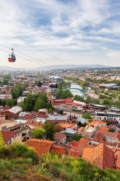 Panorama view of Tbilisi, capital of Georgia country. View from Narikala fortress. Cable road above tiled roofs.