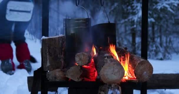 Cocinar sopa en una olla de fuego. Derretir la nieve como agua para el té. Camping de invierno en bosque . — Vídeo de stock