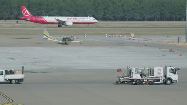 ANTALYA, TURQUÍA - 22 de mayo de 2018. Camión cisterna de gasolina Lukoil moviéndose en el campo de despegue del aeropuerto. Avión despega desde el suelo en el campo de despegue . — Vídeos de Stock