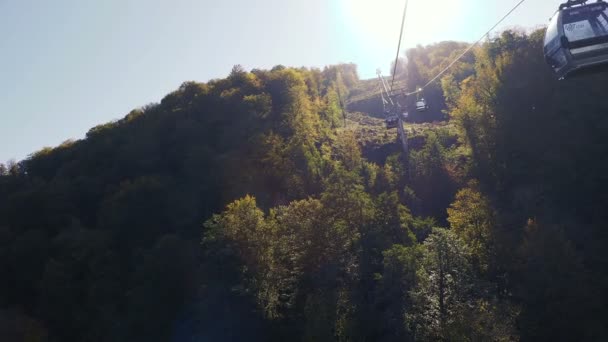ROSA-KHUTOR, RÚSSIA - 13 de outubro de 2018. Cabanas móveis da estrada por cabo. Funicular movendo-se sobre árvores nas encostas das montanhas . — Vídeo de Stock