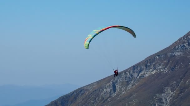 Turist med instruktör som svävar i himlen på en paraglider. Turistattraktion över Rose Peak road linbanestationen. Rosa Khutor, Ryssland. — Stockvideo
