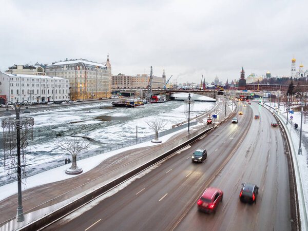 Ships with construction equipment are in Moscow-river under the bridge. Reconstruction of Bolshoy Moskvoretsky Bridge. Winter cloudy day in Moscow, Russia.