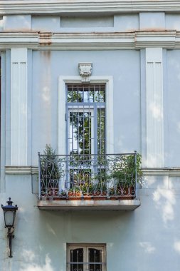 Pencere ve balkon ile ev cephe. Oda bitkiler ile eski moda balkon. Balkon süs Ferforje çit. Tiflis, Gürcistan.