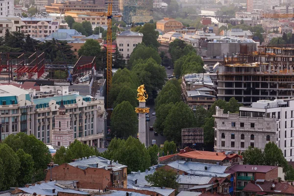 TBILISI, GEORGIA - May 01, 2017. Sunset aerial panorama view of Tbilisi. Golden Freedom Monument commonly known as the St. George Statue. — Stock Photo, Image