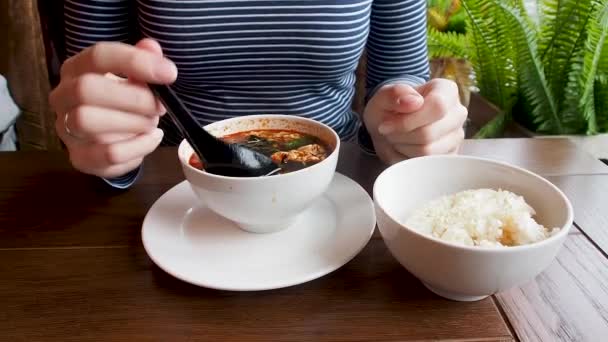 Азіатські кухні - суп кимчи в білі чаші з рисом. Жінка, помішуючи суп з ложкою — стокове відео