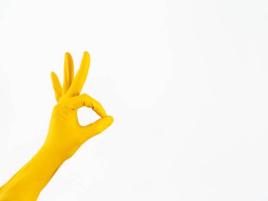 Sarı lastik eldiven elinde Tamam beyaz arka plan üzerinde gösterir. İzole Ok jest. İyi temizlik hizmeti sembolü.