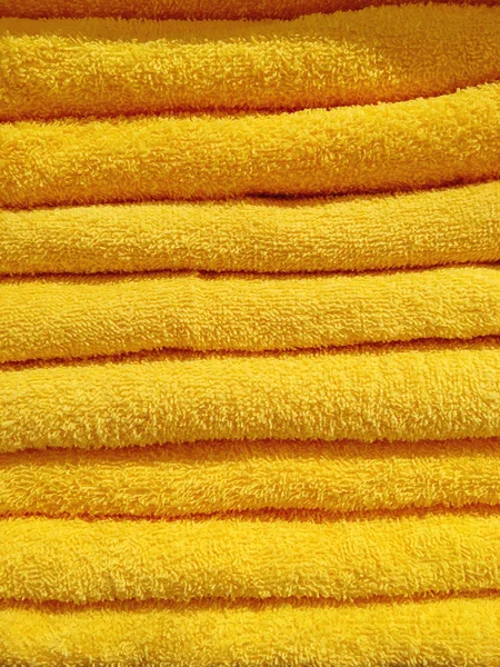 Stos żółtych ręczników frotte. Stos akcesoriów do kąpieli tekstylnych. — Zdjęcie stockowe