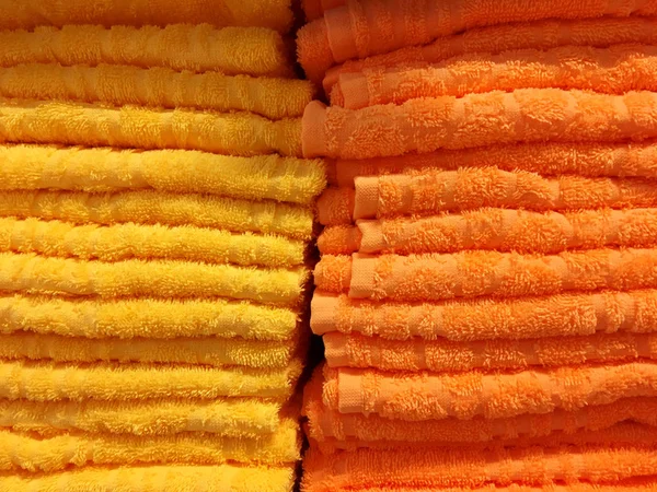 Stack of orange and yellow terry towels. Pile of textile bath accessories. — Stock Photo, Image