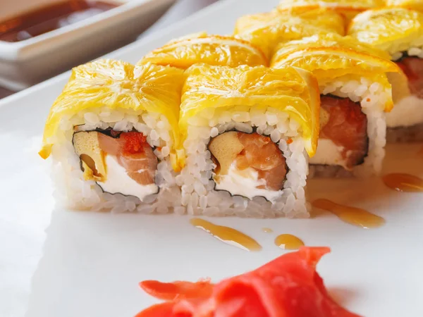 Rollos con arroz, algas nori, salmón, queso crema, huevo de pollo, caviar masago, naranja. Jengibre y salsa wasabi marinados. Cocina asiática, plato tradicional - sushi . — Foto de Stock