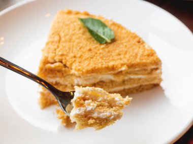 Tatlım pasta beyaz plakalı. Lezzetli tatlı ekşi krema ile. Metal kaşık pasta küçük bir ısırık ile.