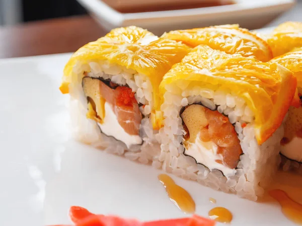 Rollos con arroz, algas nori, salmón, queso crema, huevo de pollo, caviar masago, naranja. Jengibre y salsa wasabi marinados. Cocina asiática, plato tradicional - sushi . — Foto de Stock