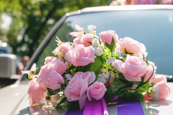 Artificial pink roses with ribbons. Car decoration for wedding ceremony.