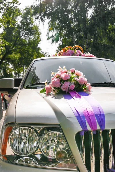 Artificial pink roses and golden rings with bells. Car decoration for wedding ceremony.
