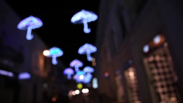 Decorazione esterna a forma di ombrelli. Carino lampadine colorate brillano al buio. sfondo sfocato e sfocato. Yalta, Crimea . — Video Stock