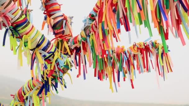 Многоцветные тканевые ленты, раскачивающиеся на ветру. Древняя традиция связывания лент на ветвях деревьев для привлечения удачи и исполнения желаний. Крым . — стоковое видео