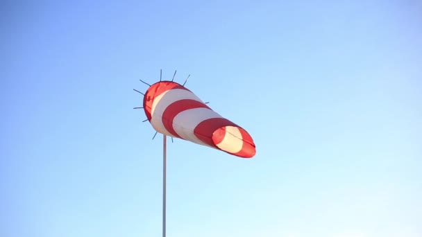 Ventilador vermelho e branco listrado contra um céu azul claro . — Vídeo de Stock