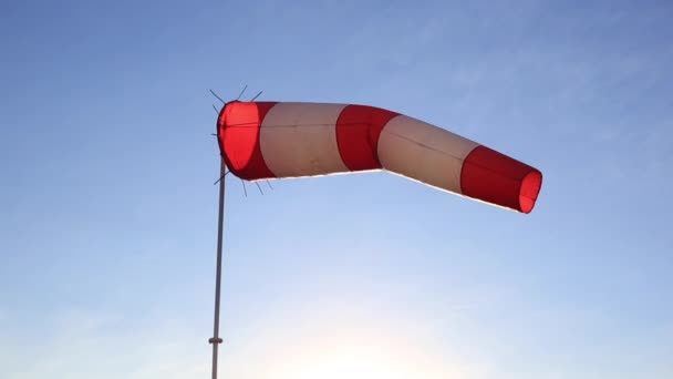 Rot-weiß gestreifte Windfahne vor blauem Himmel. — Stockvideo