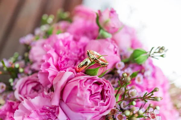 Anillos de boda dorados en ramo de novia con rosas rosadas y lila. Composición floral tradicional para ceremonia de boda . — Foto de Stock